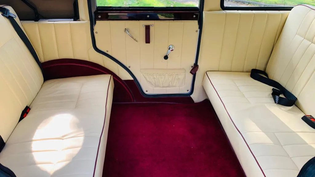 Interior view of the two cream leather bench seats facing each other with deep burgundy carpet