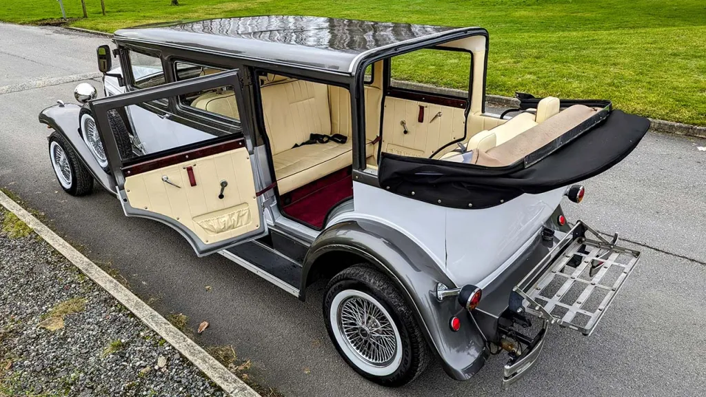 Aerial view of vintage limousine with roof open and rear cabin door open shwoing cream interior and red carpet
