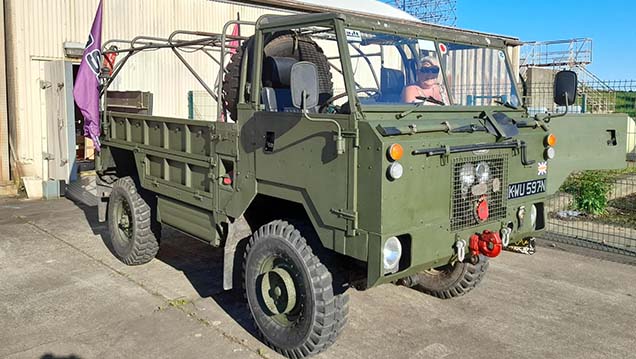 Side view of Army green Land Rover Truck without rear canvas