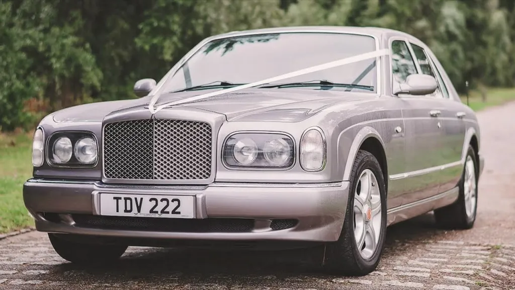 Front Left Side of Silver bentley with white ribbons showing front grill