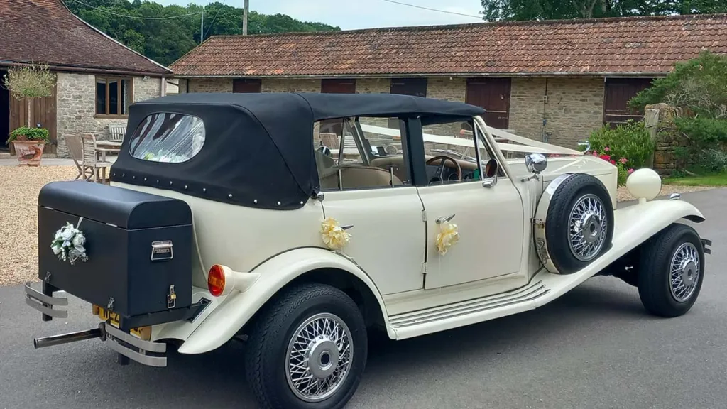 Rear side view of Beauford Convertible with black roof close, black pinc nic trunk at the rear with white wedding bow on it