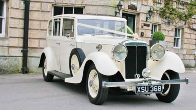 Front side view of White Vintage Rolls-Royce decorated with White Ribbons accros Bonnet