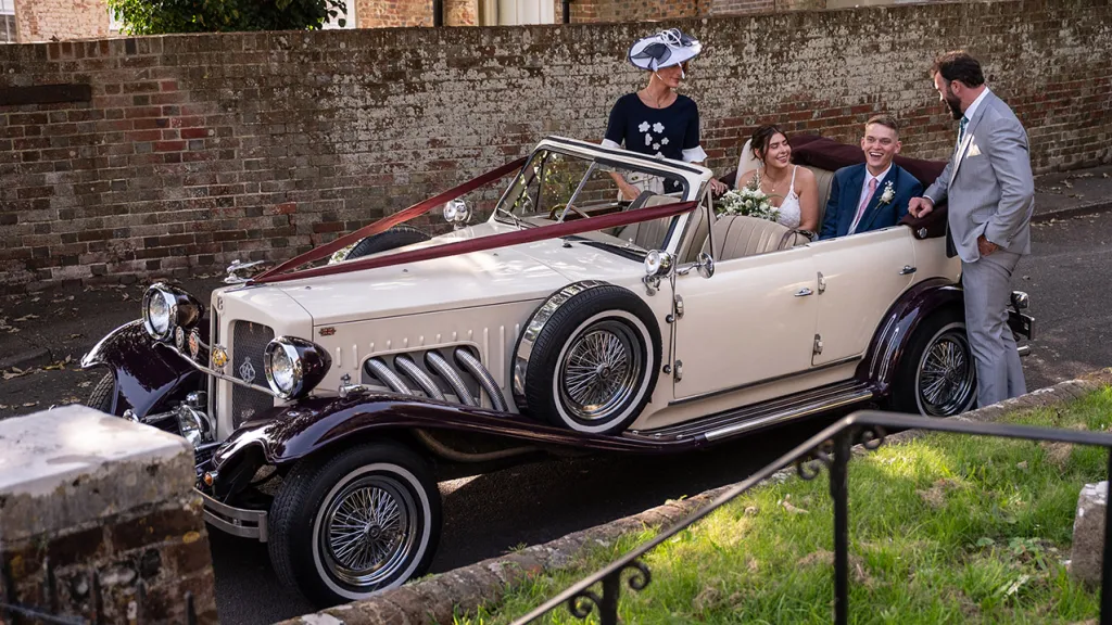 Aerial View of Convertible Vintage Beauford with Bride and her father seating in the rear of the vehicle with groom and his mother standing by the vehicle