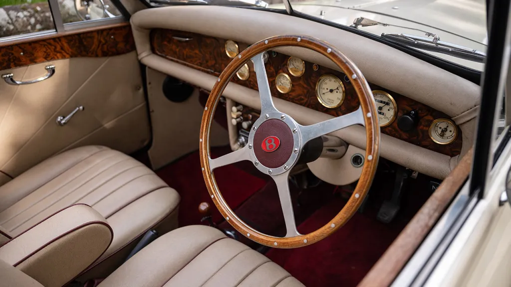 Front Seating area with cream leather interior and deep red Carpet and wooden dashboard surrounded by cream leather dashboard on the top