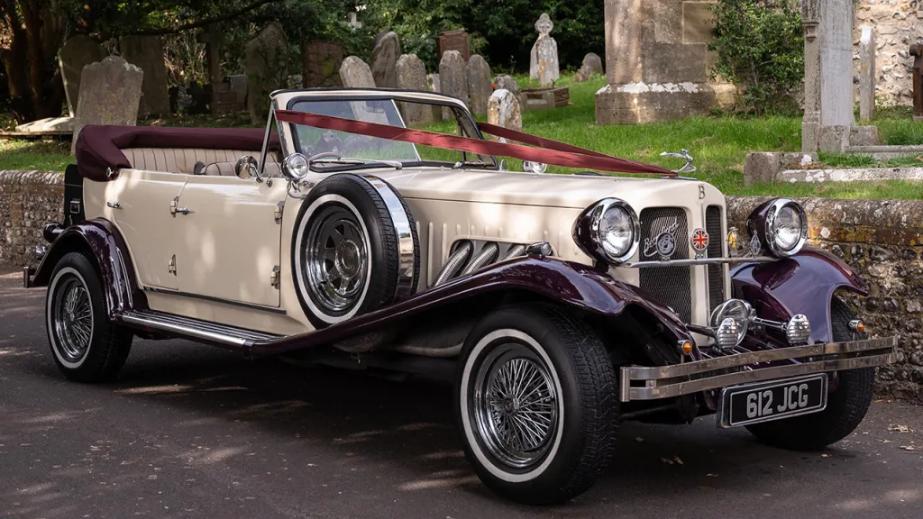 Side view of Convertible Vintage Beauford in Ivory with Burgundy Wheel arches with spare wheel mounted on the side skirt