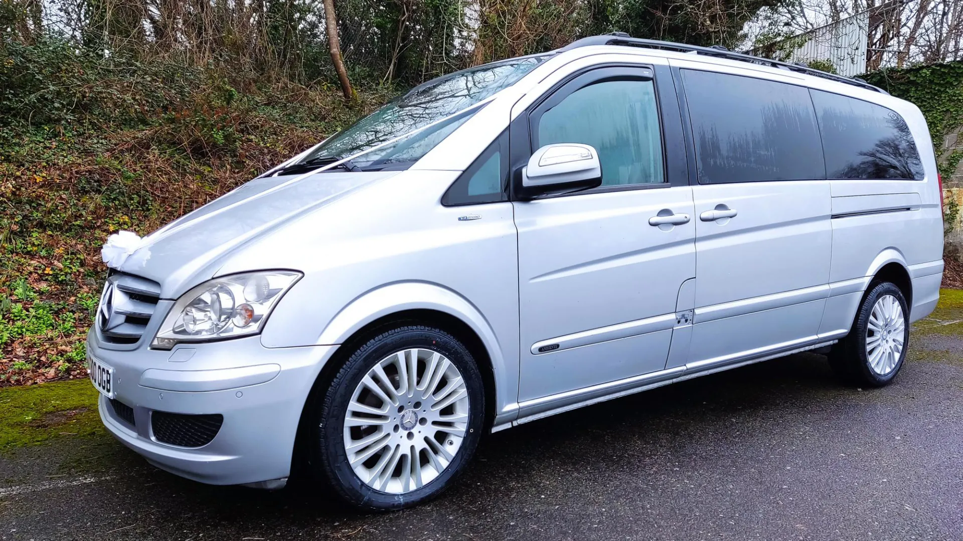 Side view of Silver 7-seater Mercedes Viano decorated with white ribbons
