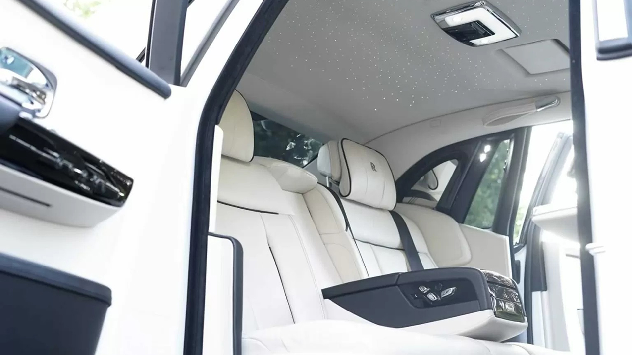 interior rear seating area of Rolls-Royce Phantom 8. Interior is white leather