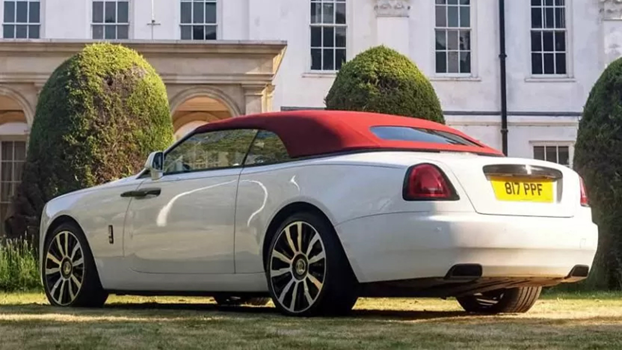 Rear side view of Rolls-Royce Dawn with burgundy soft top closed in the garden of a wedding venue in Essex