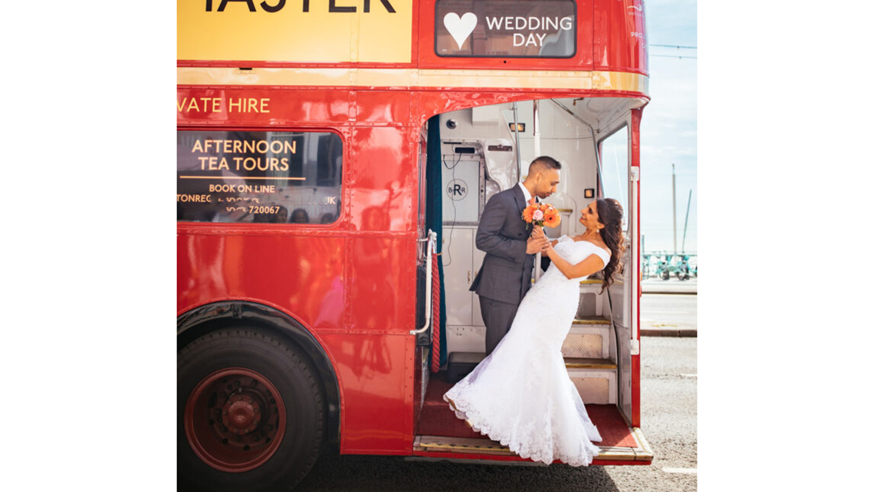 Bride and Groom posing for photos standing on the rear open platform of the Routemaster