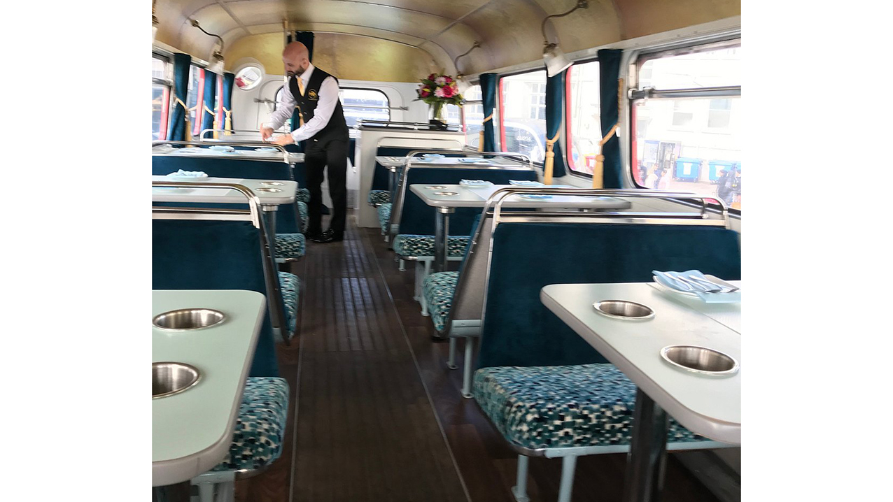 waiter standing inside the bus lower deck area setting tables