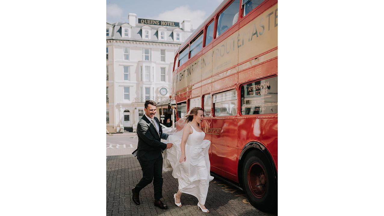 Bride and groom walking towards the rear open platform of red routemaster bus