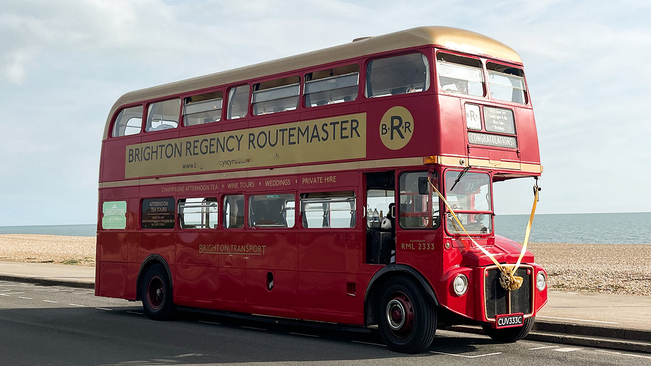 Front side view of Red Routemaster bus on Brighton sea view with view of the beach and sea in the background