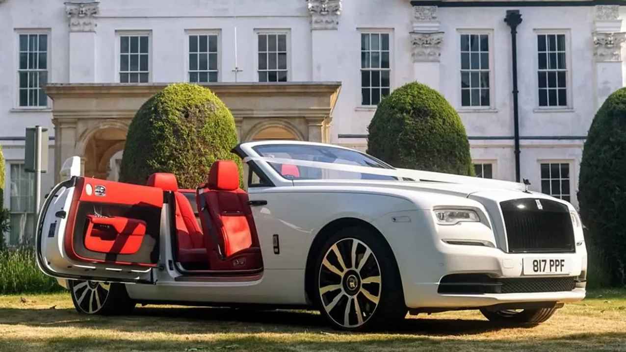 White Rolls-Royce Dawn Convertible with roof down and door open showing deep burgundy leather interior.