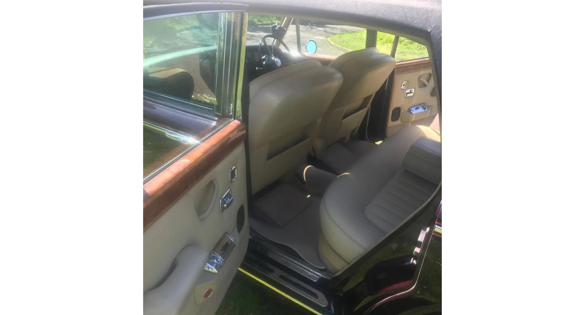 Cream interior rear seat with door open of Rolls-Royce. Showing large amount of legroom