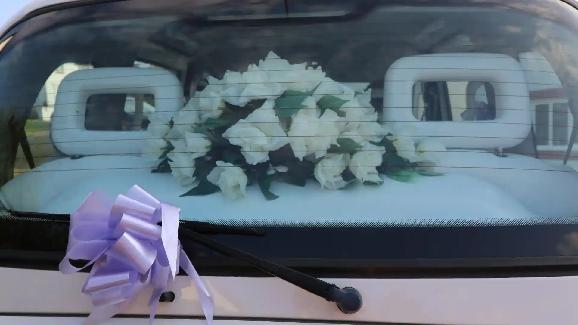 Wedding Flowers on rear parcel shelf viewed from outside through the rear window, Light Purple Bow attached to windscreen wiper