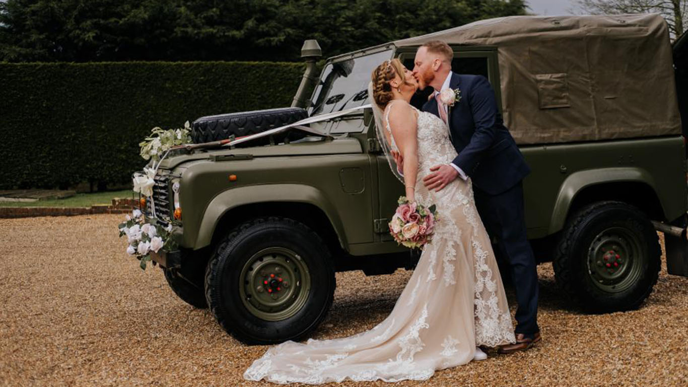 Bride and Groom kissing in front of a Army Greem Landrover
