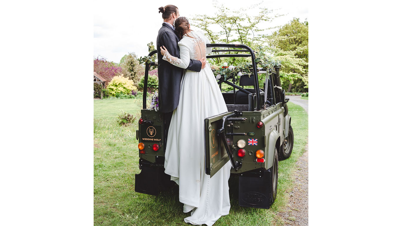 Bride and Groom hugging standing up in the back of the Military Khaki Green Landrover