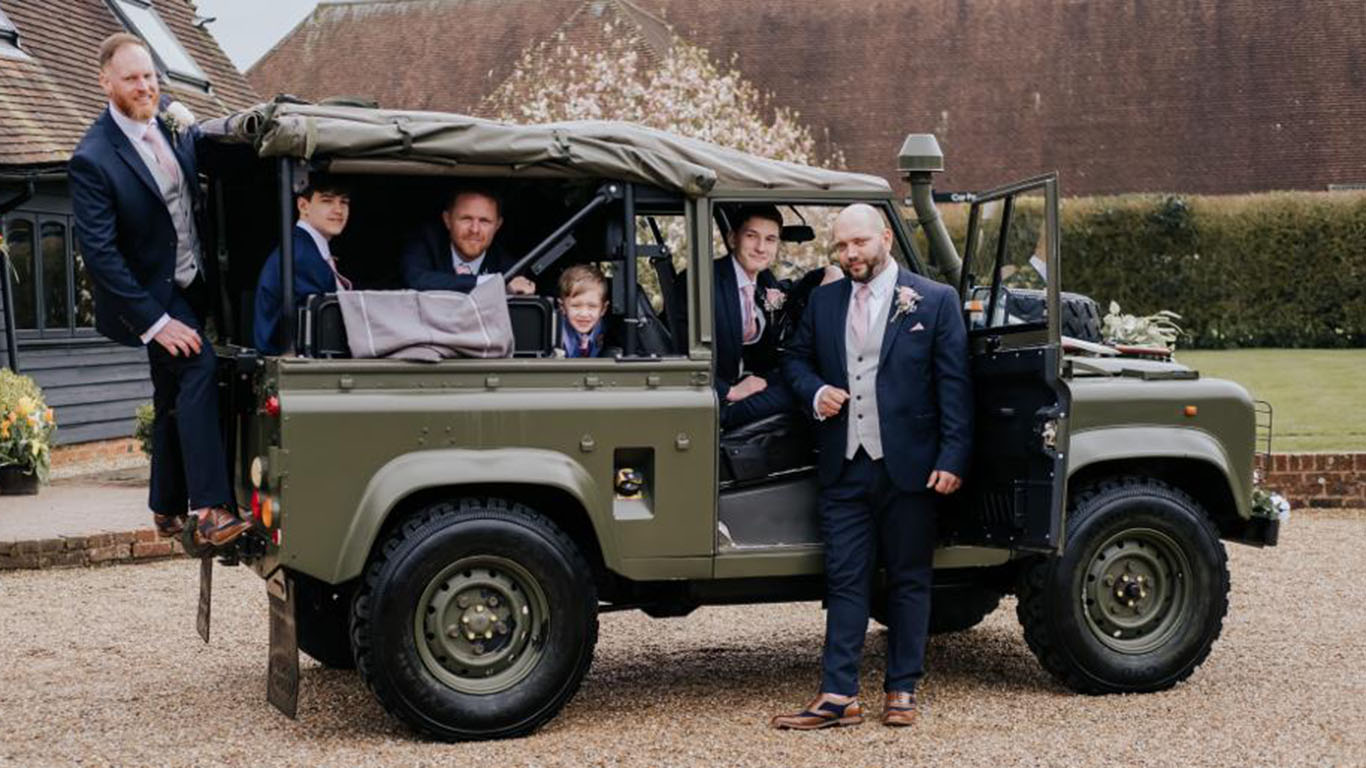 Groomsmen seating in rear of the Landrover with side canvas open