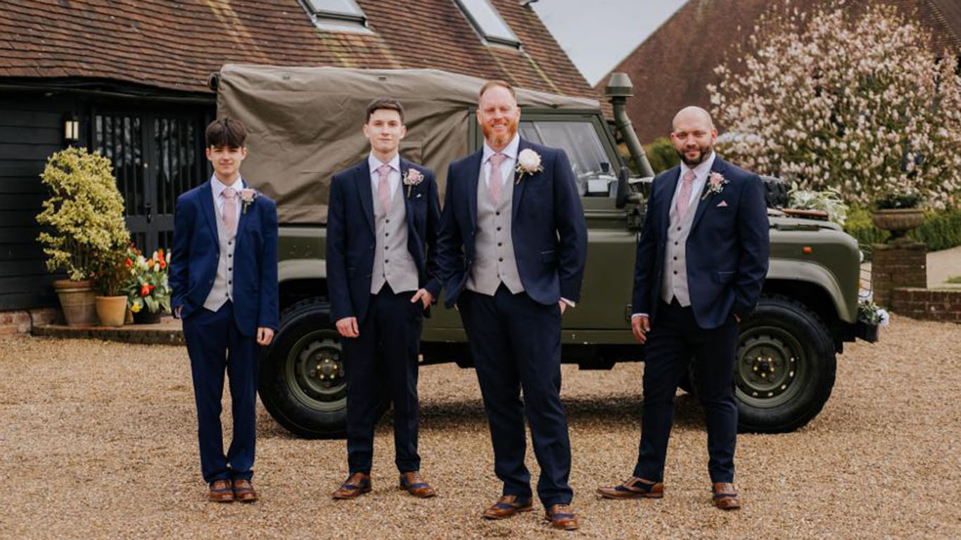 Four Groomsmen standing in front of a Military Vehicle
