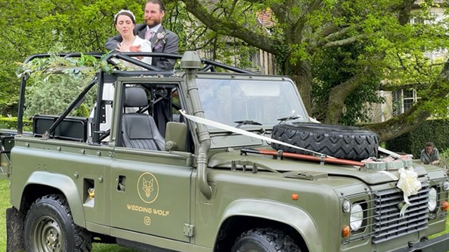 Bride and Groom standing up in the back of the Landrover for photos