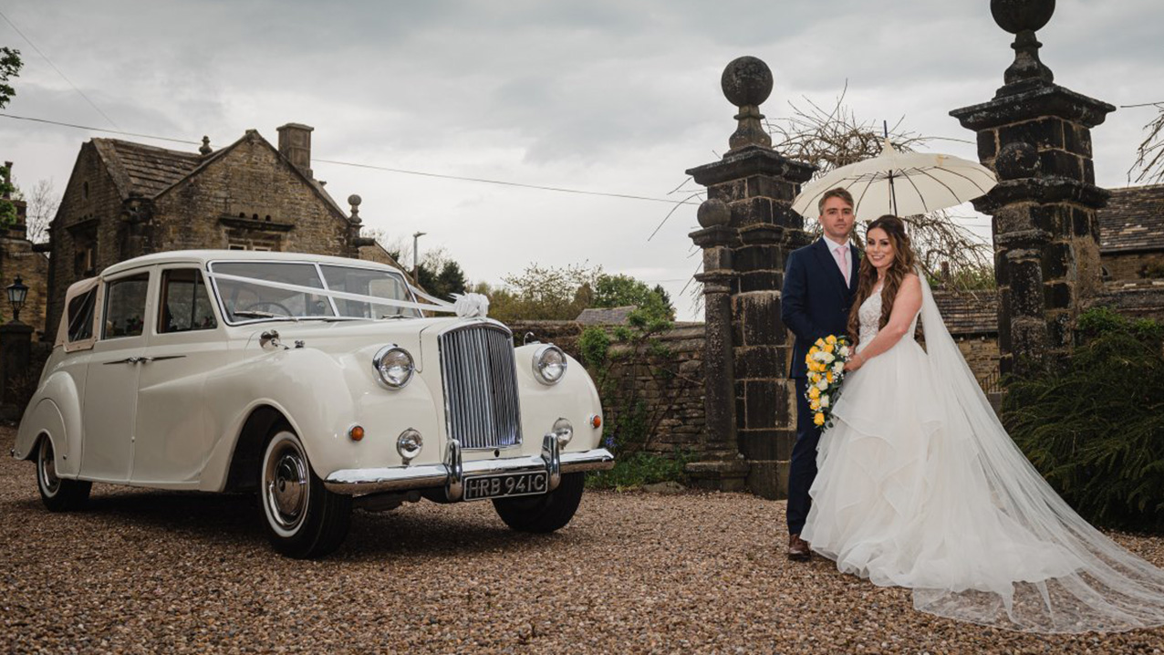 Bride and Groom stansing in front of the classic Austin Princess Limousine