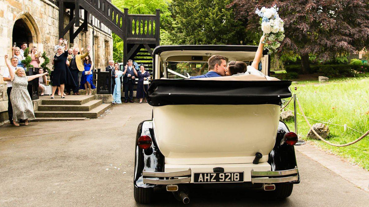 Rear view of Bramwith Landaulette with roof down showing Bride and Groom kissing