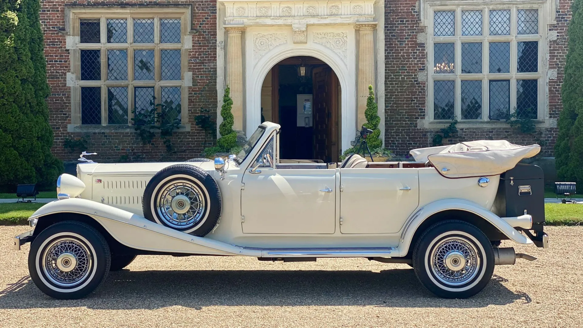 Full Side view of Beauford Convertible with roof down and tucked aweay under Cream Cover. White Wall Tires and spare wheel mounted on skirt