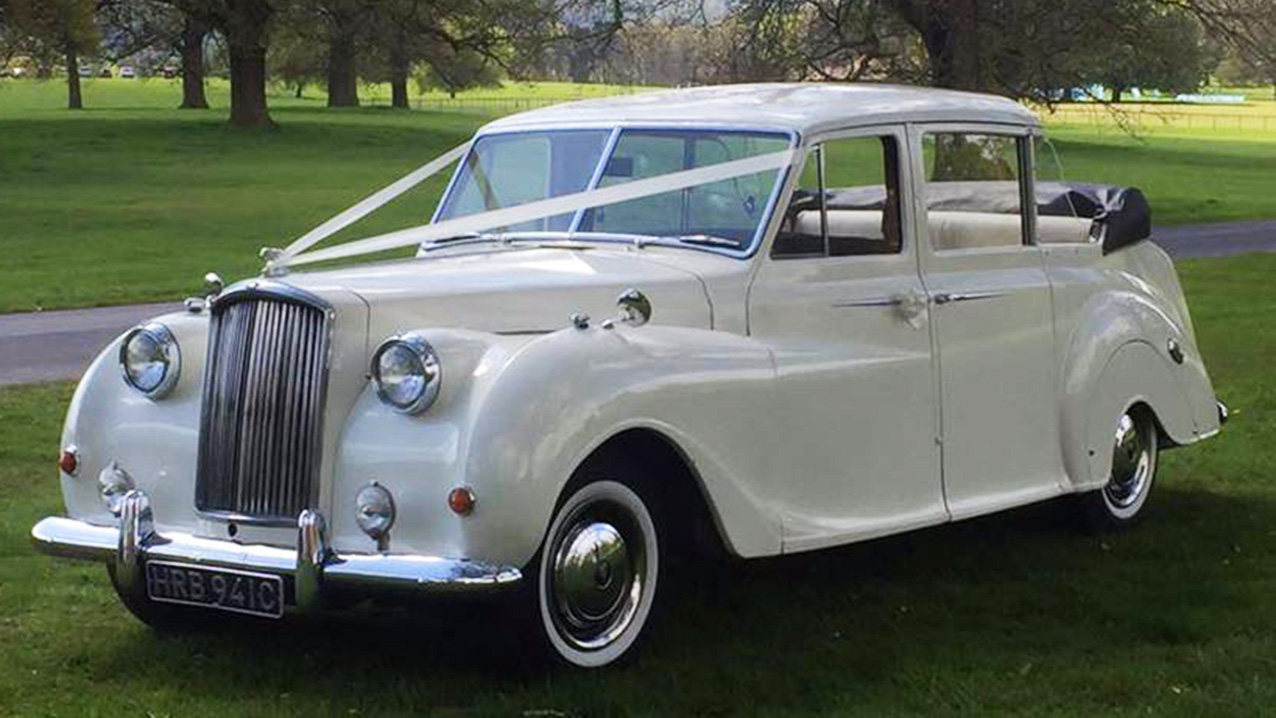 Convertible Classic austin Princess with roof down and dressed with White Ribbons across the front bonnet.