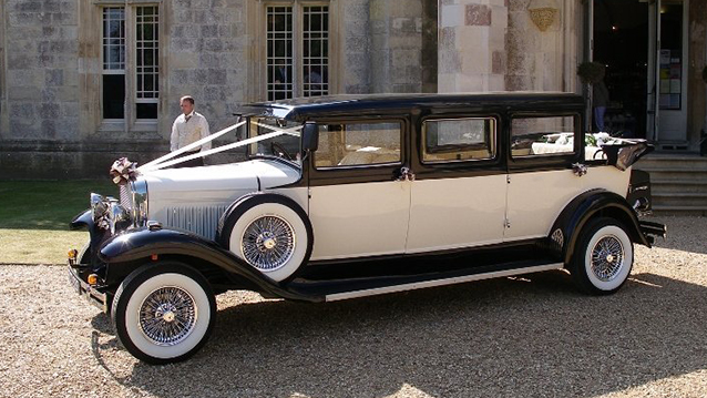 Front Side view of Vintage Bramwith convertible with White Ribbons in front of wedding venue