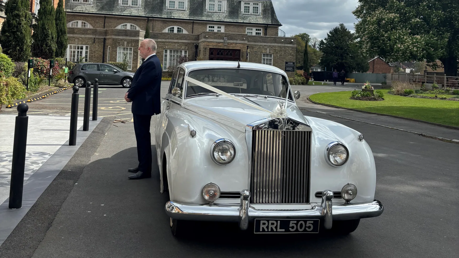 Classic Rolls-Royce silver Cloud with chauffeur waiting next to the vehicle