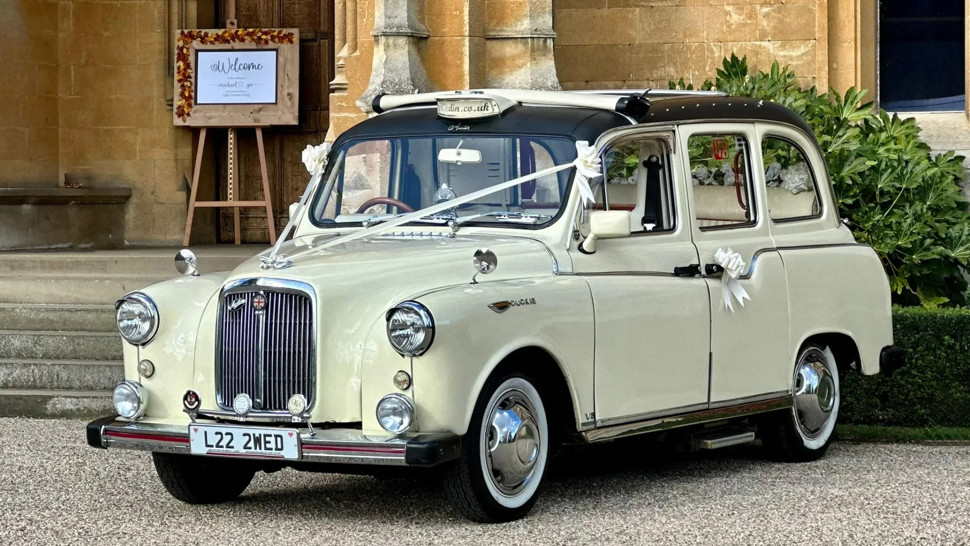 Front view classic Taxi Cab decorated with white ribbons in front of wedding venue in Essex