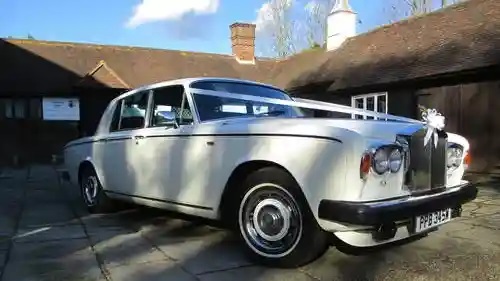 Right side view of Classic Rolls-Royce dressed with traditional White Ribbons accross its bonnet waiting outside wedding venue in Devon