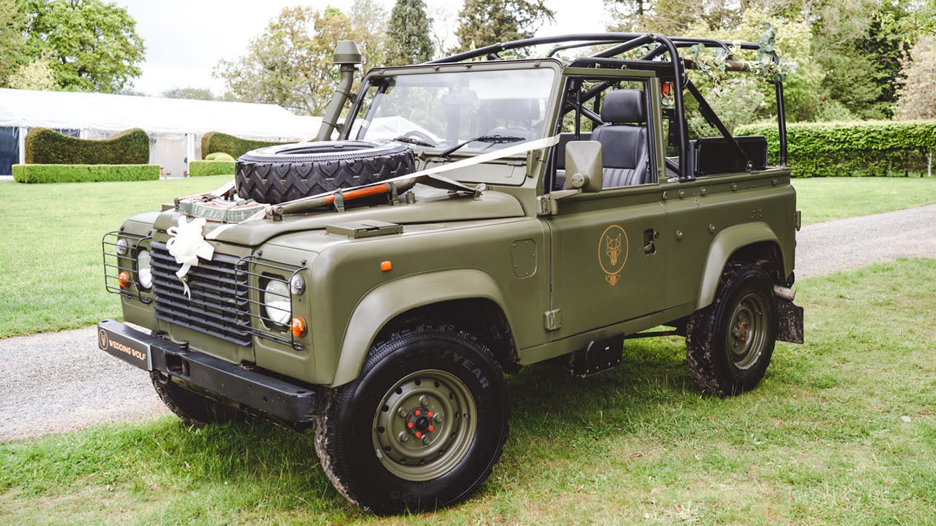 Side view of Military Landrover with canvas off, Spare wheel on bonnet and dressed with traditional Wedding Ribbon