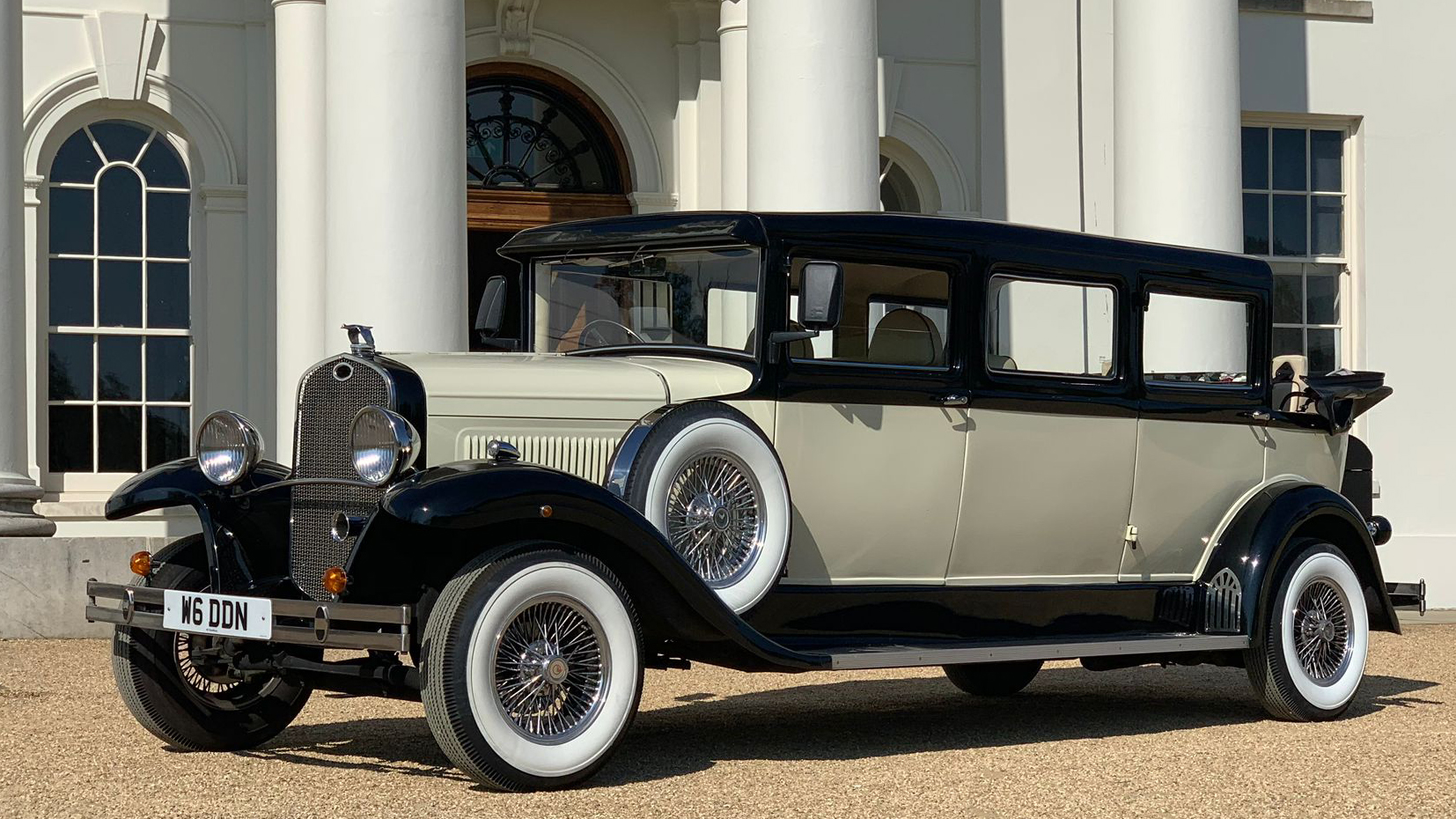 Vintage style Ivory Bramwith with black roof and black wheel arches in front of wedding venue