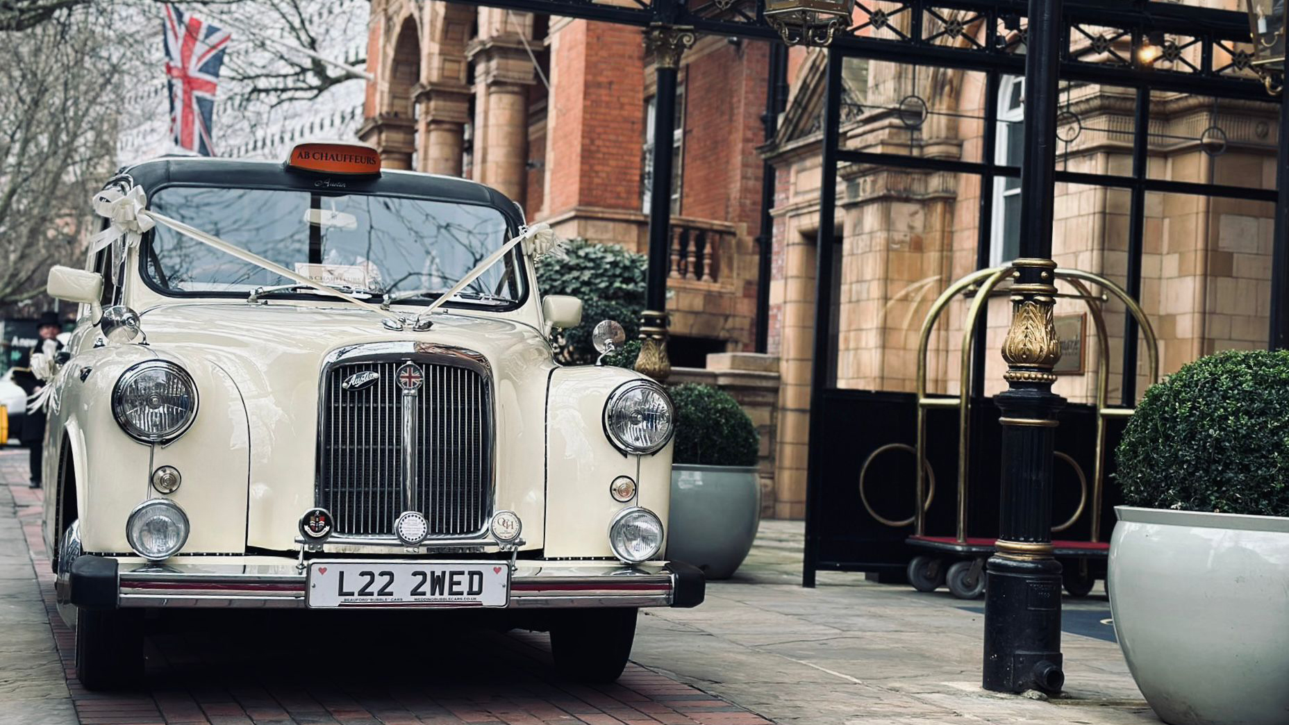 Classic Taxi Cab decorated with traditional wedding ribbons in white in front of wedding venue in London