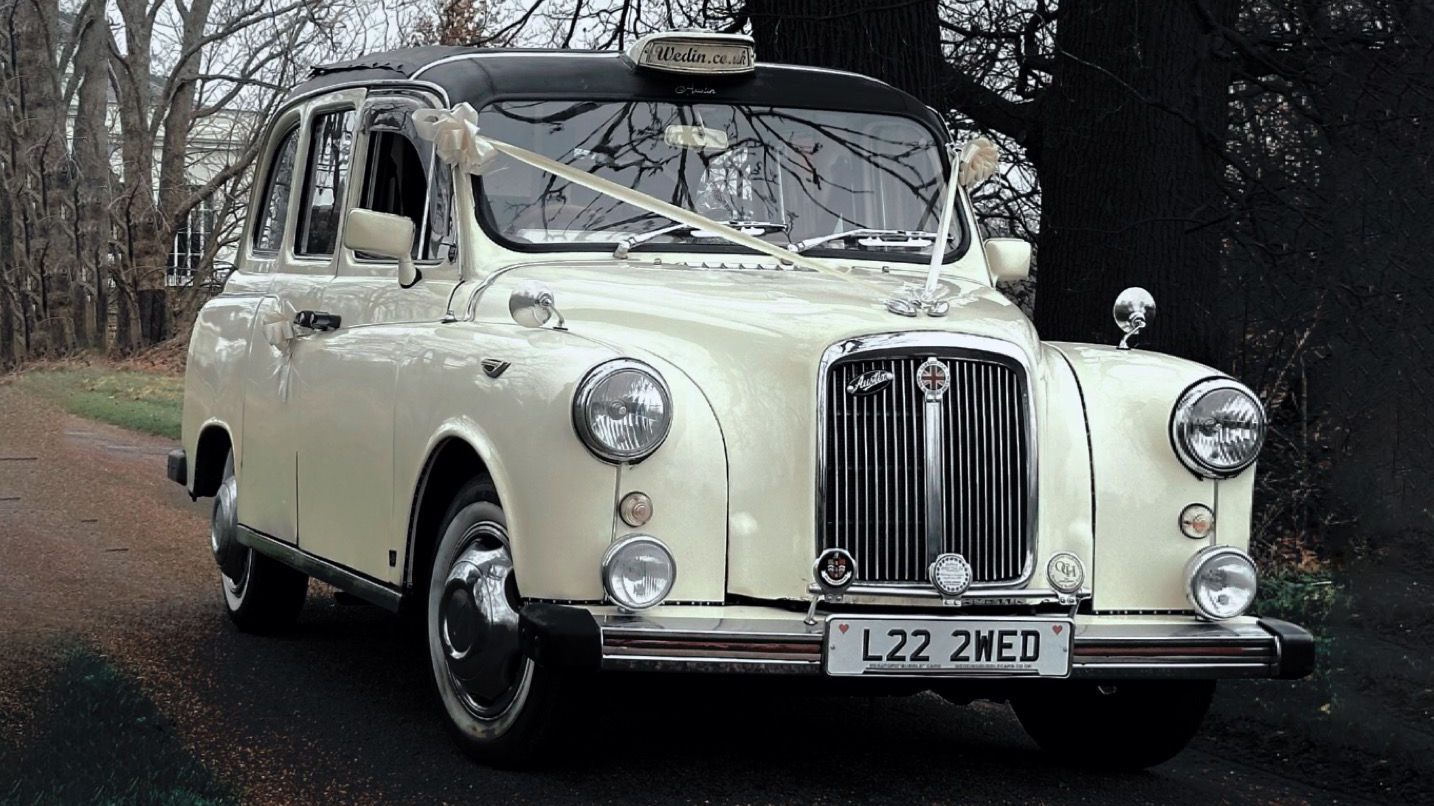 Classic Taxi Cab with with ribbons, Chrome alloy wheels entering wedding venue