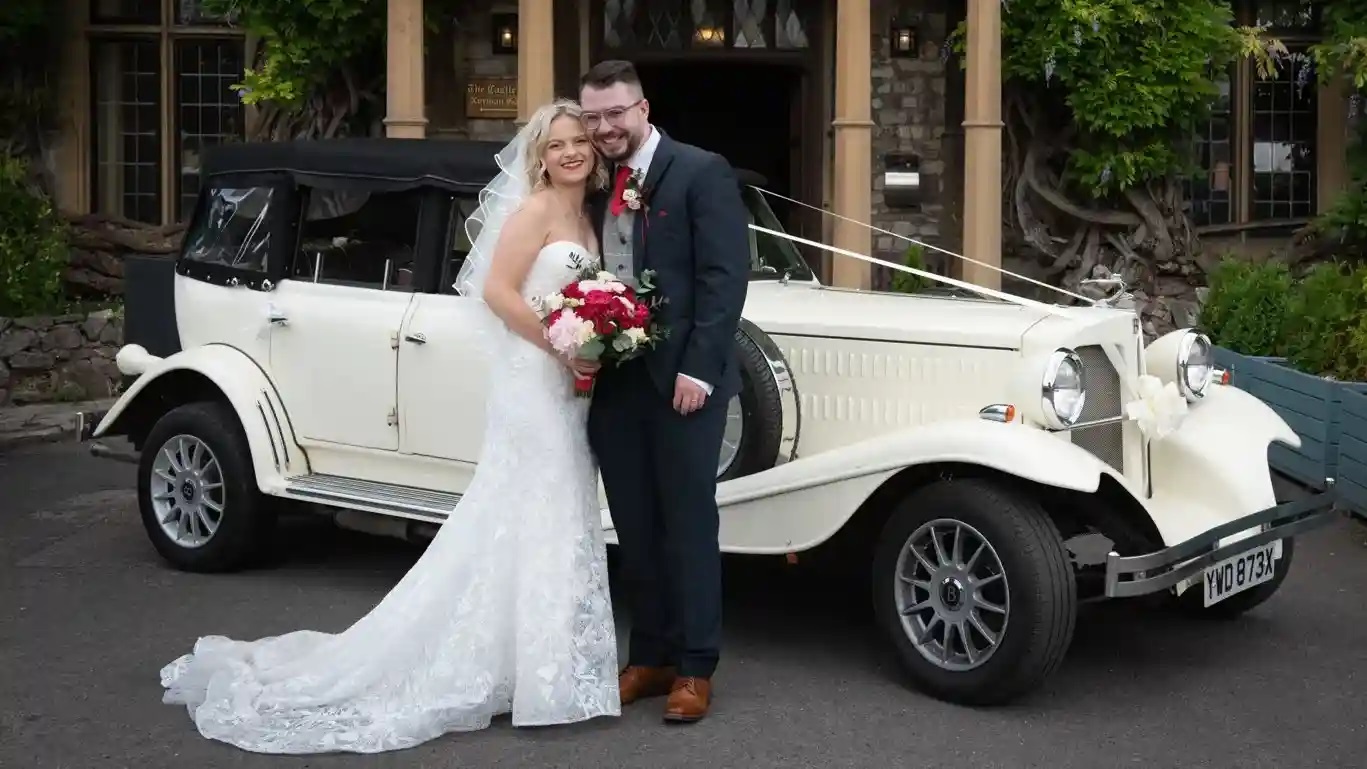 Bride and Groom in front of a  Beauford decorated with traditional white ribbons