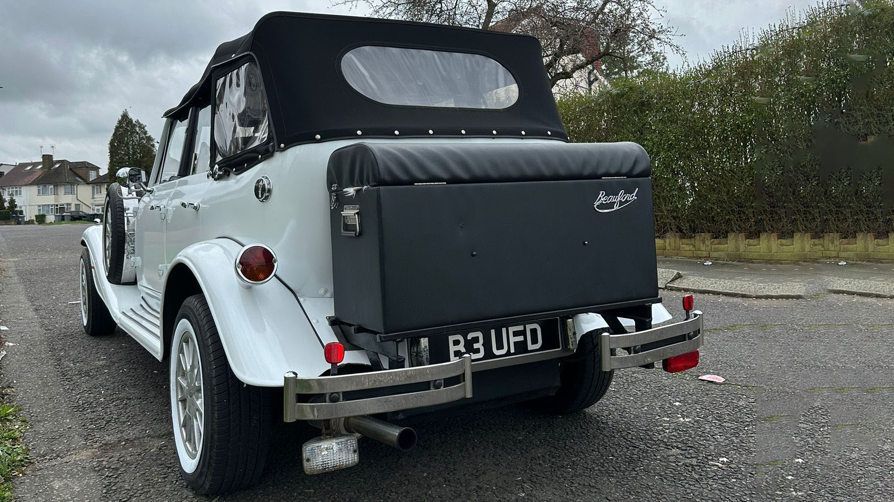 Rear view from White Beauford 4-Door Convertible with black picnis table at the rear of the vehicle