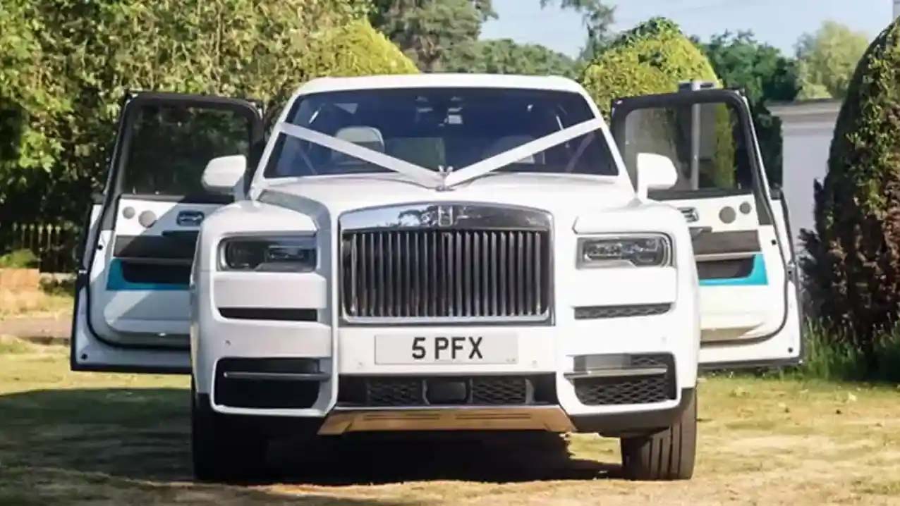Front View of Rolls-Royce Cullinan showing the chrome grill with both rear hinged doors open and decorated with traditional white ribbons accross its bonnet