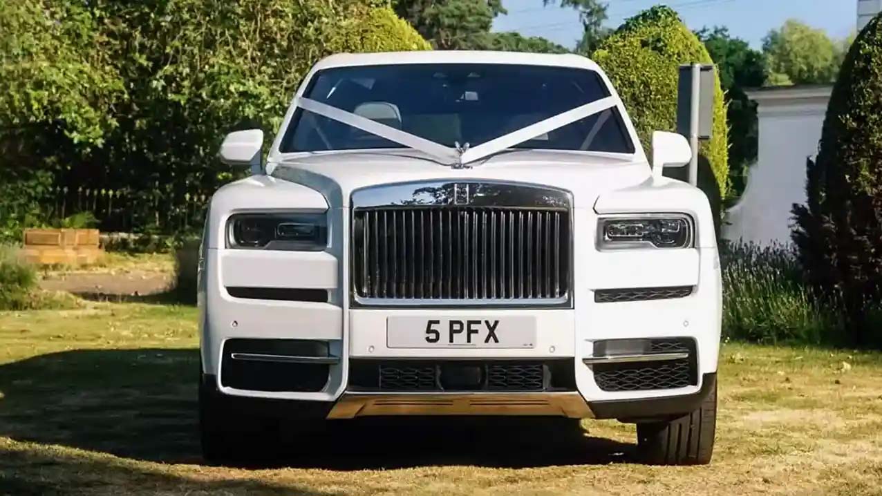 Front View of Rolls-Royce Cullinan showing the chrome grill and decorated with traditional white ribbons accross its bonnet