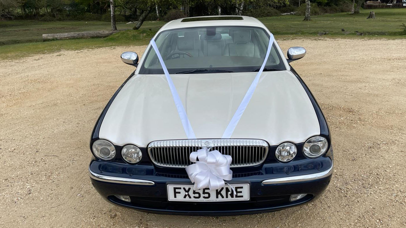 Full front view of Modern Daimler decorated with White wedding ribbons and Bow on its fron grill