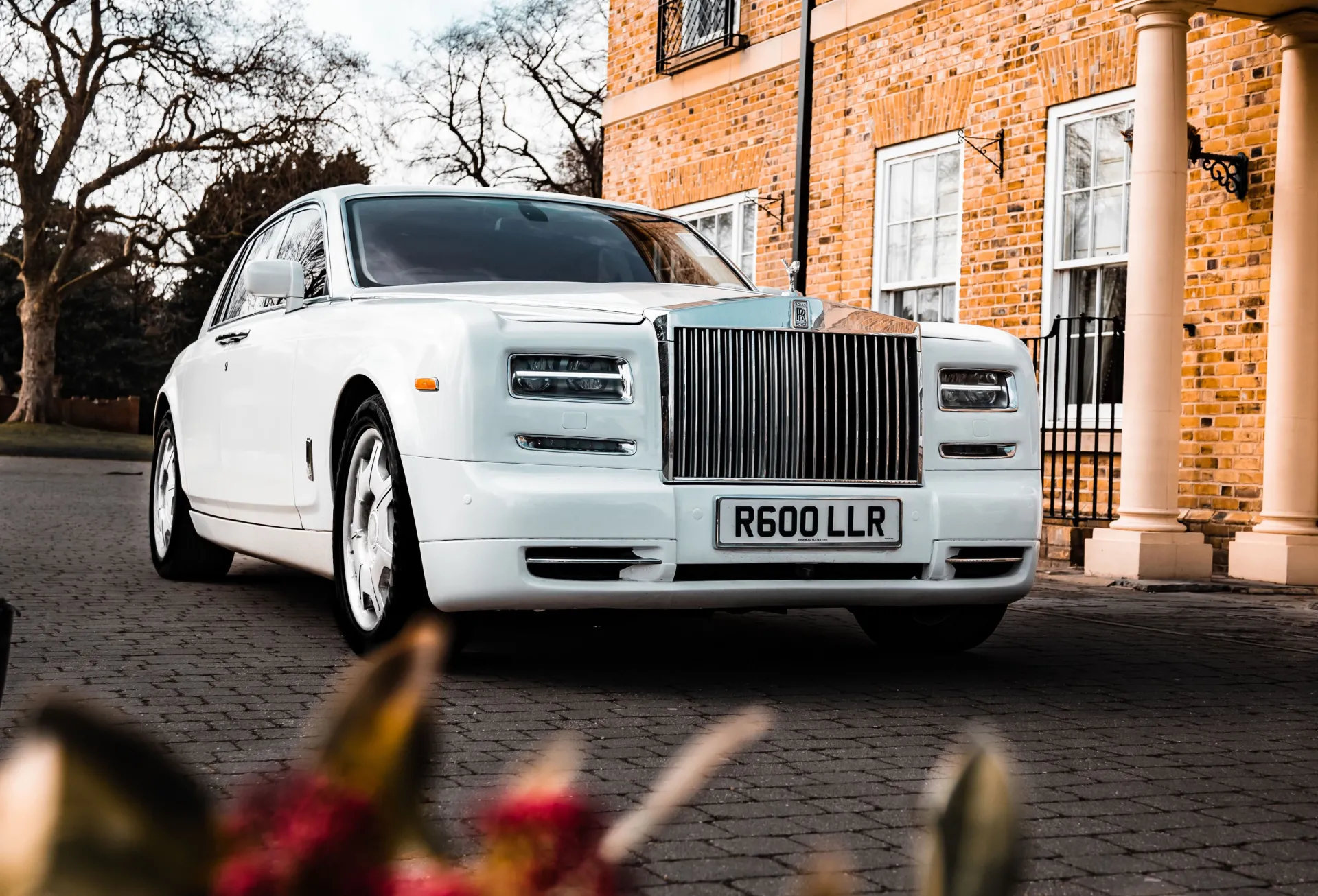 Luxurious White Rolls-Royce phantom in front of a wedding venue.