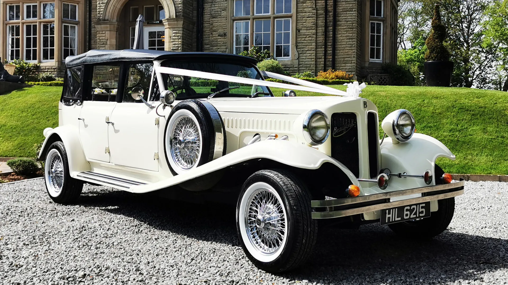 Ivory Beauford Convertible with black soft top roof up  dressed with white ribbons across the bonnet