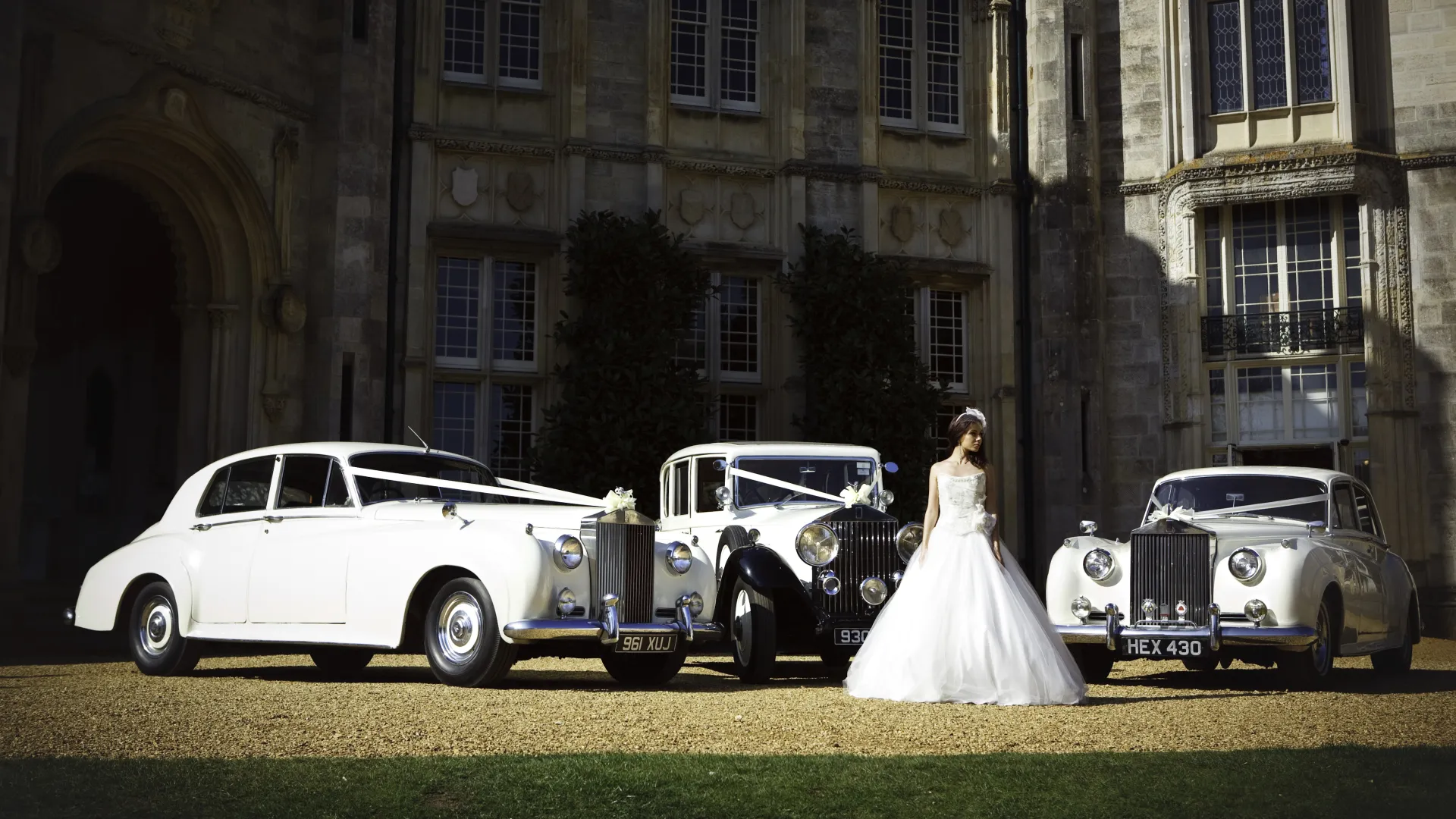 A Double Decker Routemaster Bus Leaving the Venue and a White Classic Rolls-Royce Entering the South Wales Wedding Venue. Both decorated with White Ribbons.