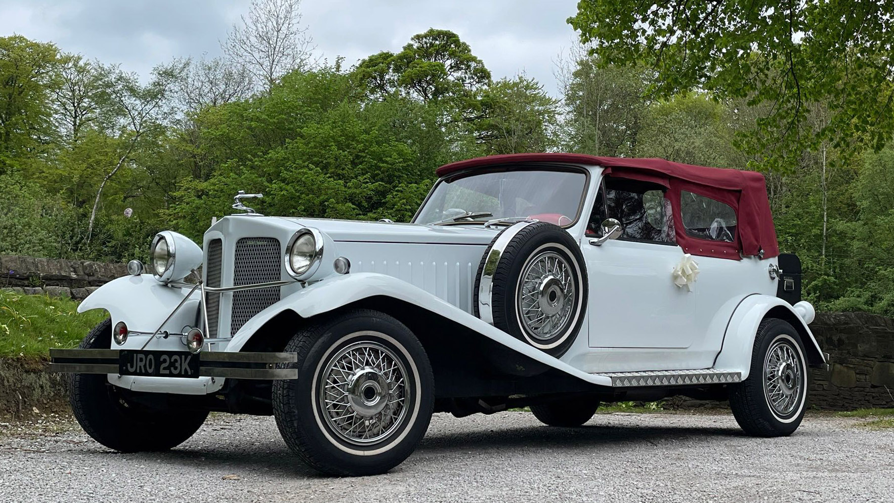Left Side view of White Beauford with white wall tires and burgundy soft top close