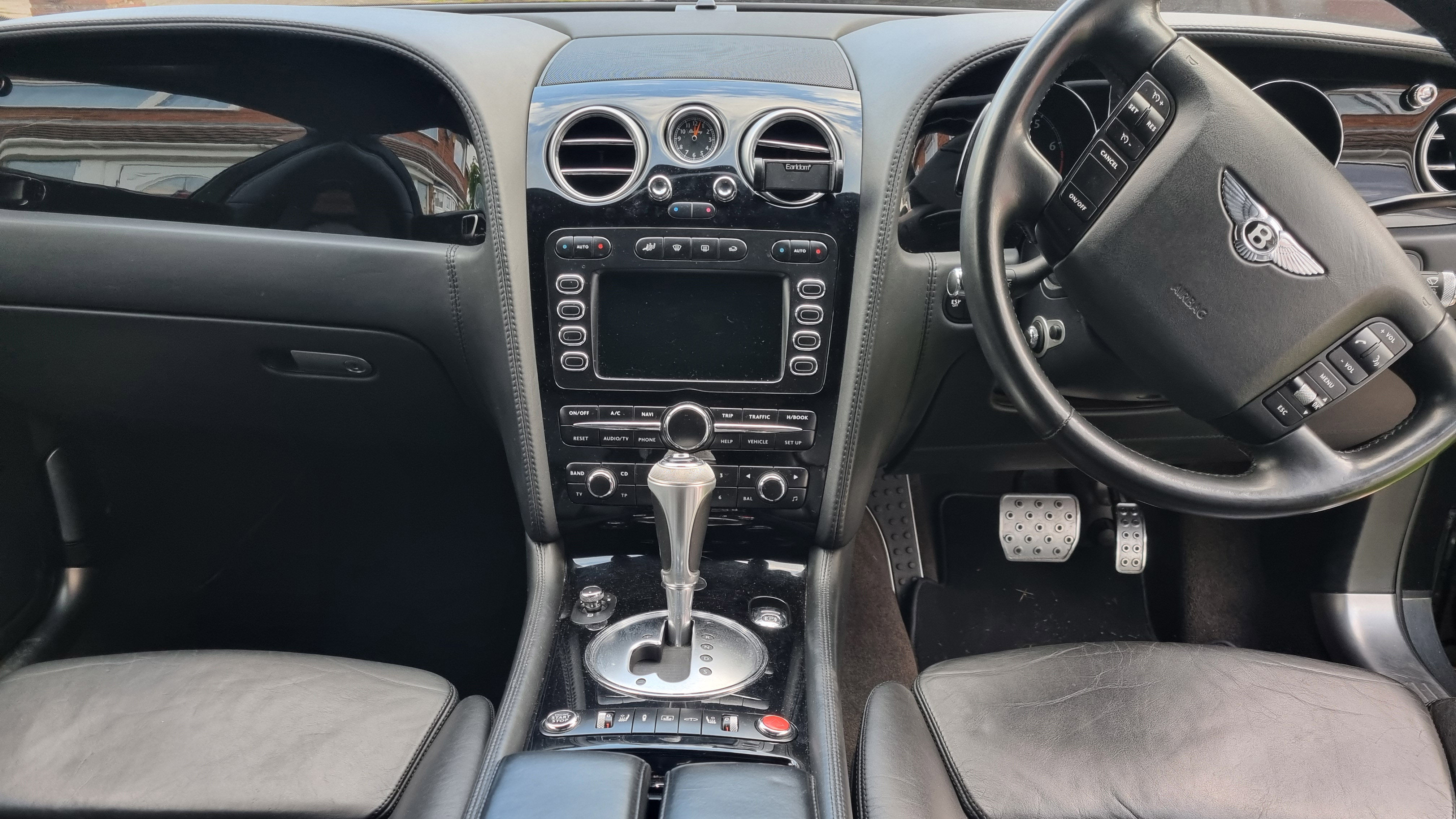 Front interior view of the Bentley's Dashboard and steering wheel from the rear passengers view
