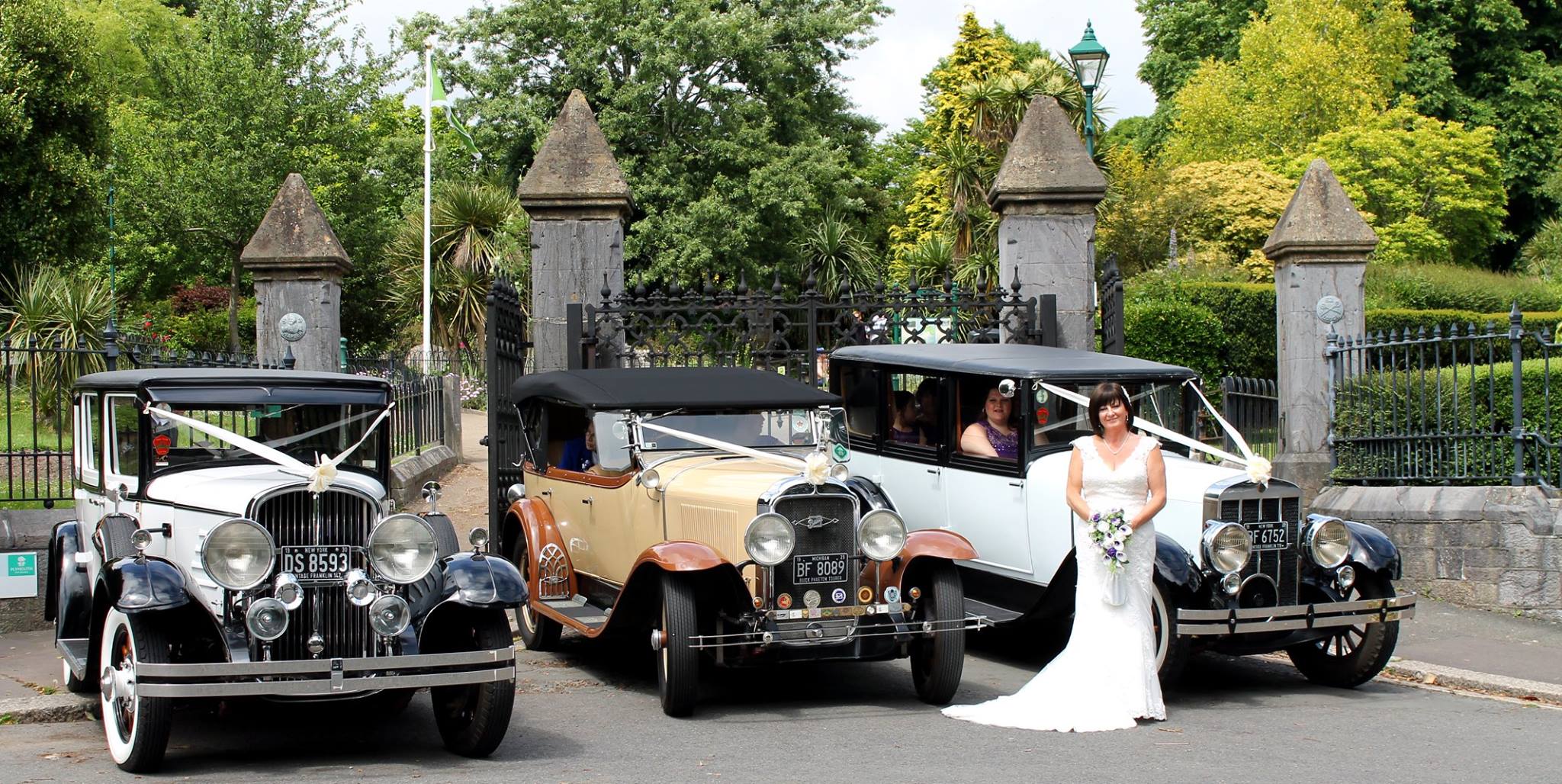 Selection of 3 Vintage cars with Bride wearing a white dress in front of the vehicles