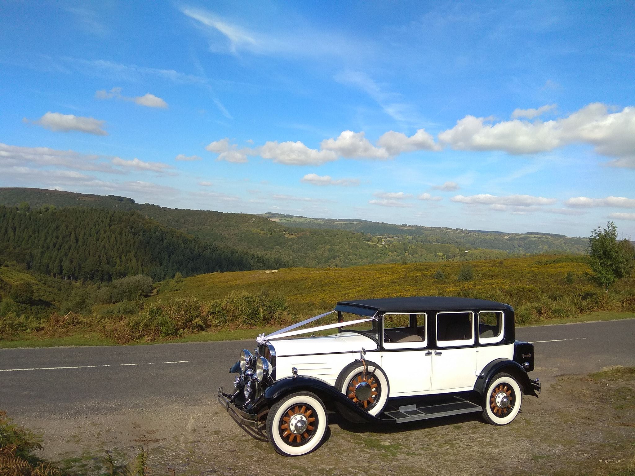 White Vintage Wedding Car on Devon's Coast with view over the countryside in the background