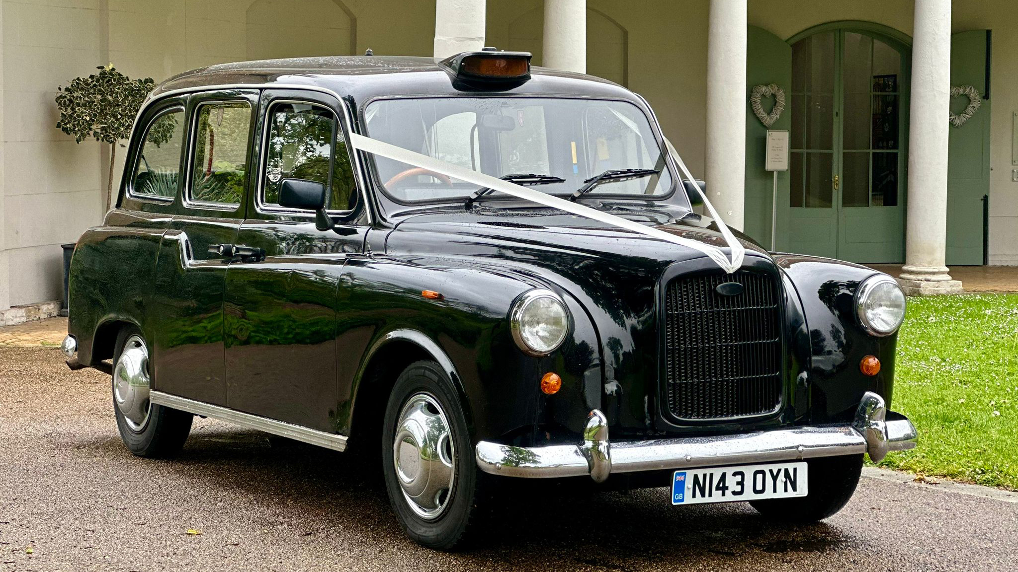 Front Side view of Classic Black Taxi Cab decorated with ivory wedding ribbons