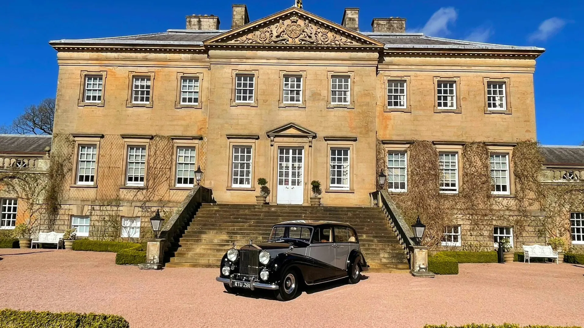 Vintage Rolls-Royce in Front of the main entrance of Dumfries House in Cumnock on a bright blue-sky day